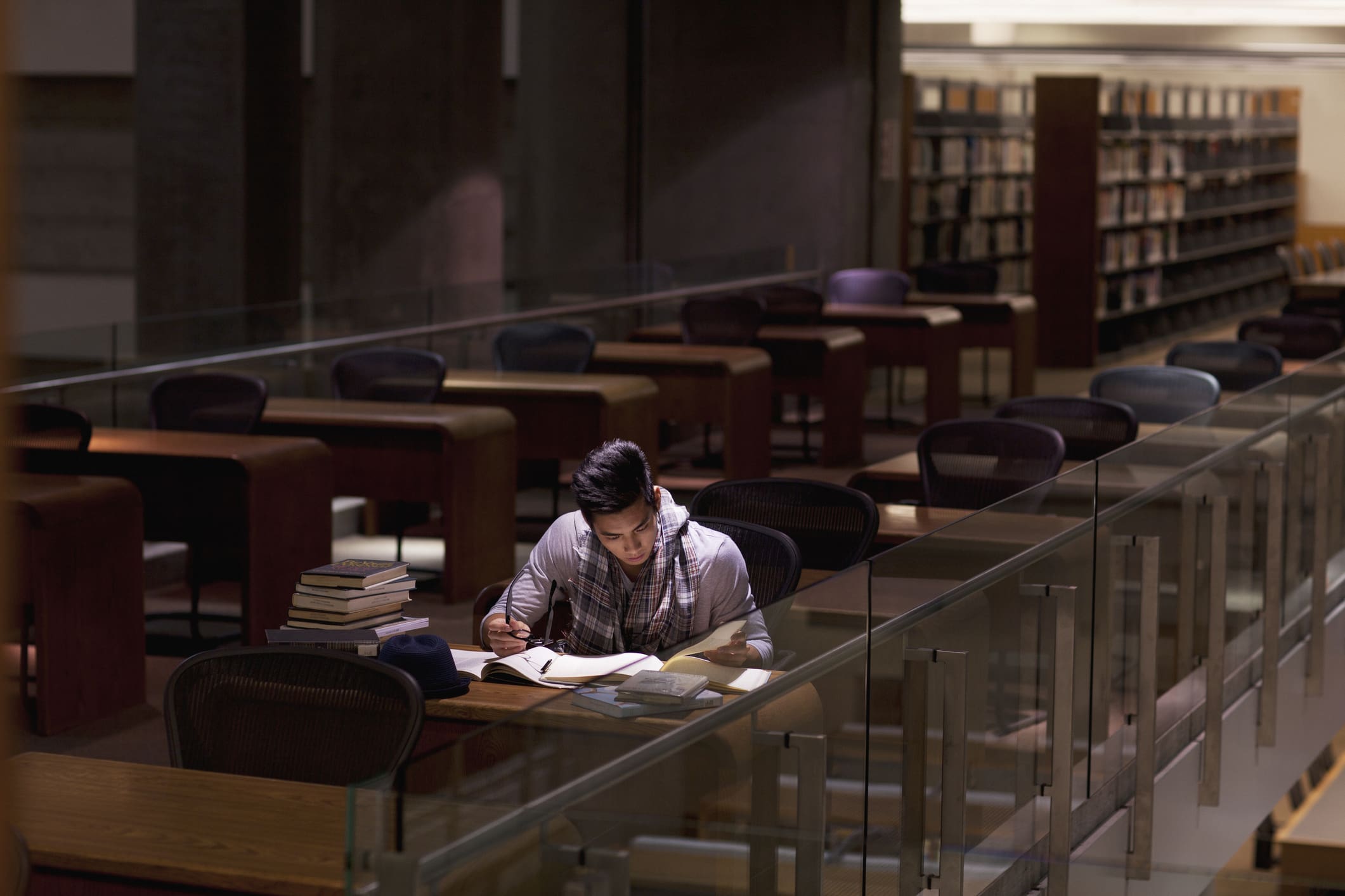 A person studying alone in a dimly lit library.