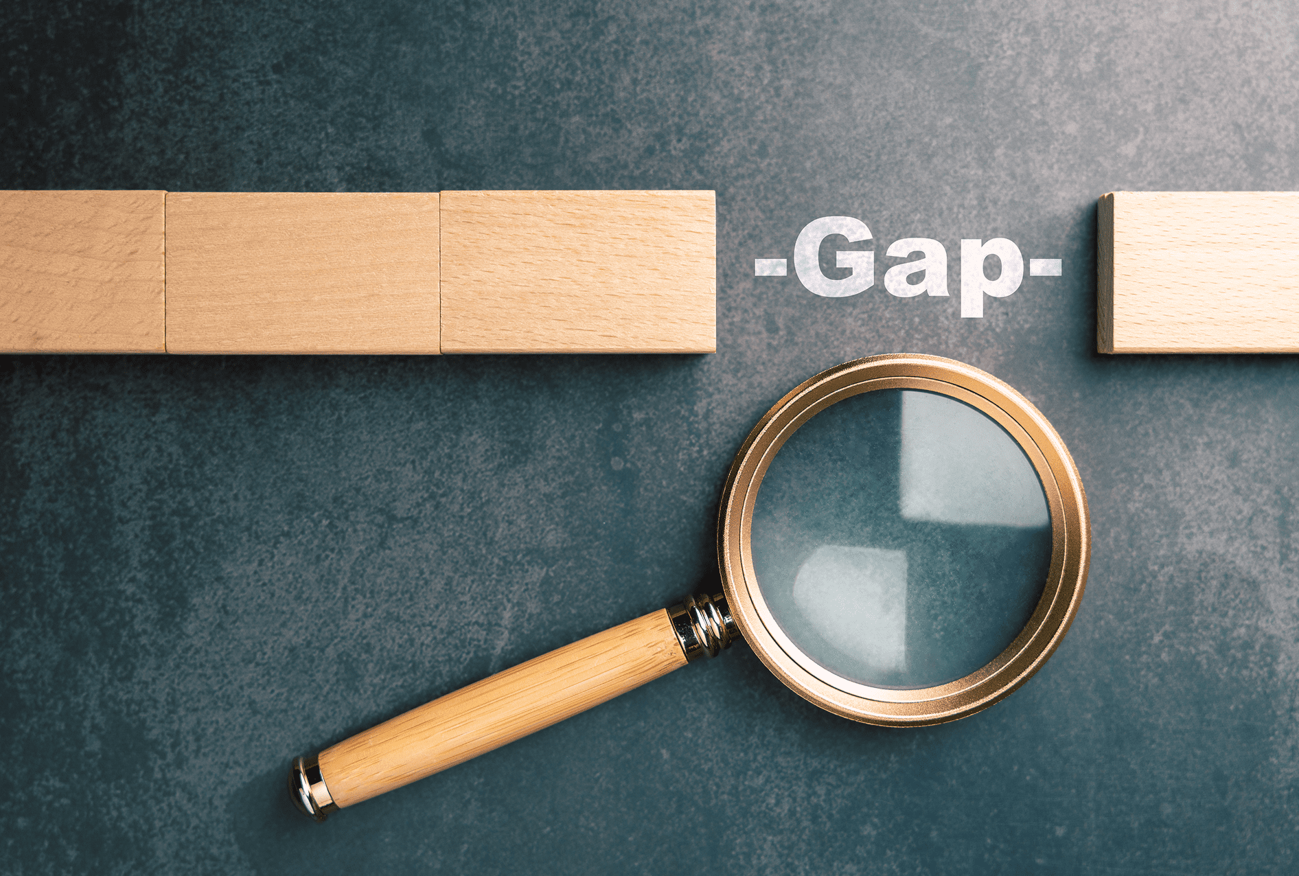 Wooden block next to a magnifying glass with the word 'Gap'.