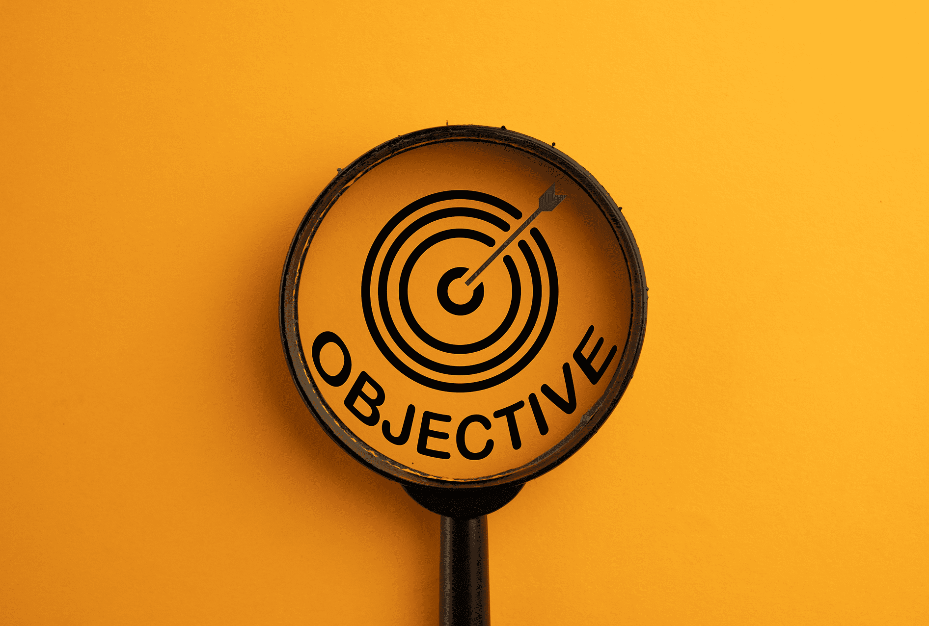 Magnifying glass focusing on a target labeled 'Objective'.