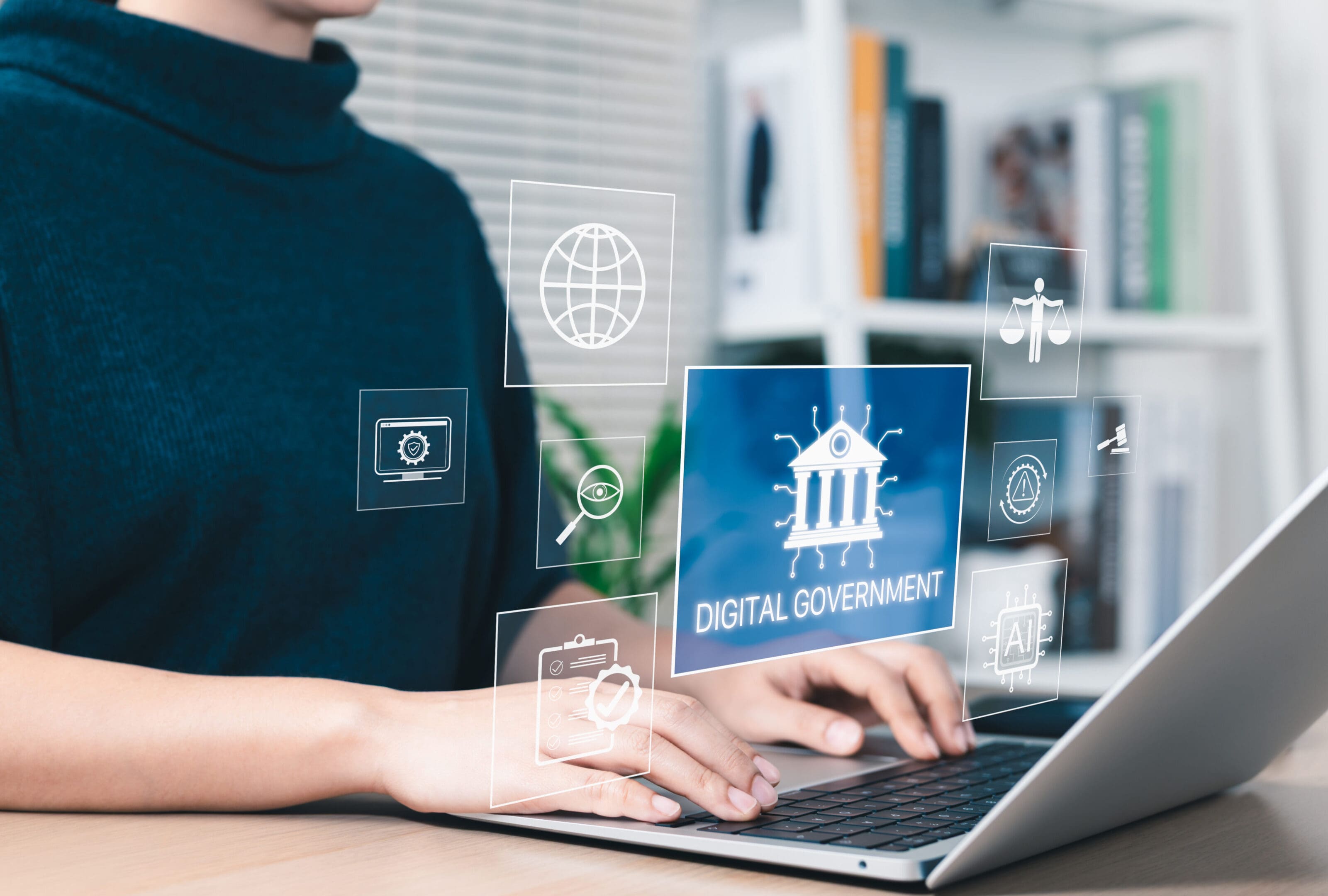 Person using laptop with digital government icons floating above the keyboard.