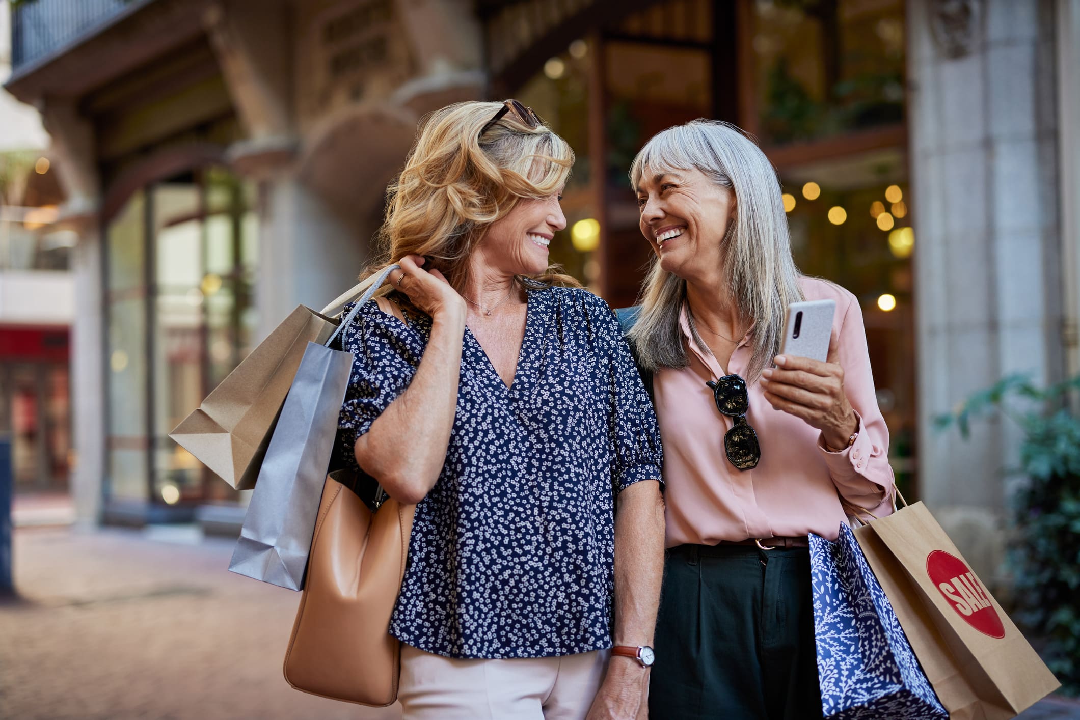 Two older women smiling and chatting while shopping together.
