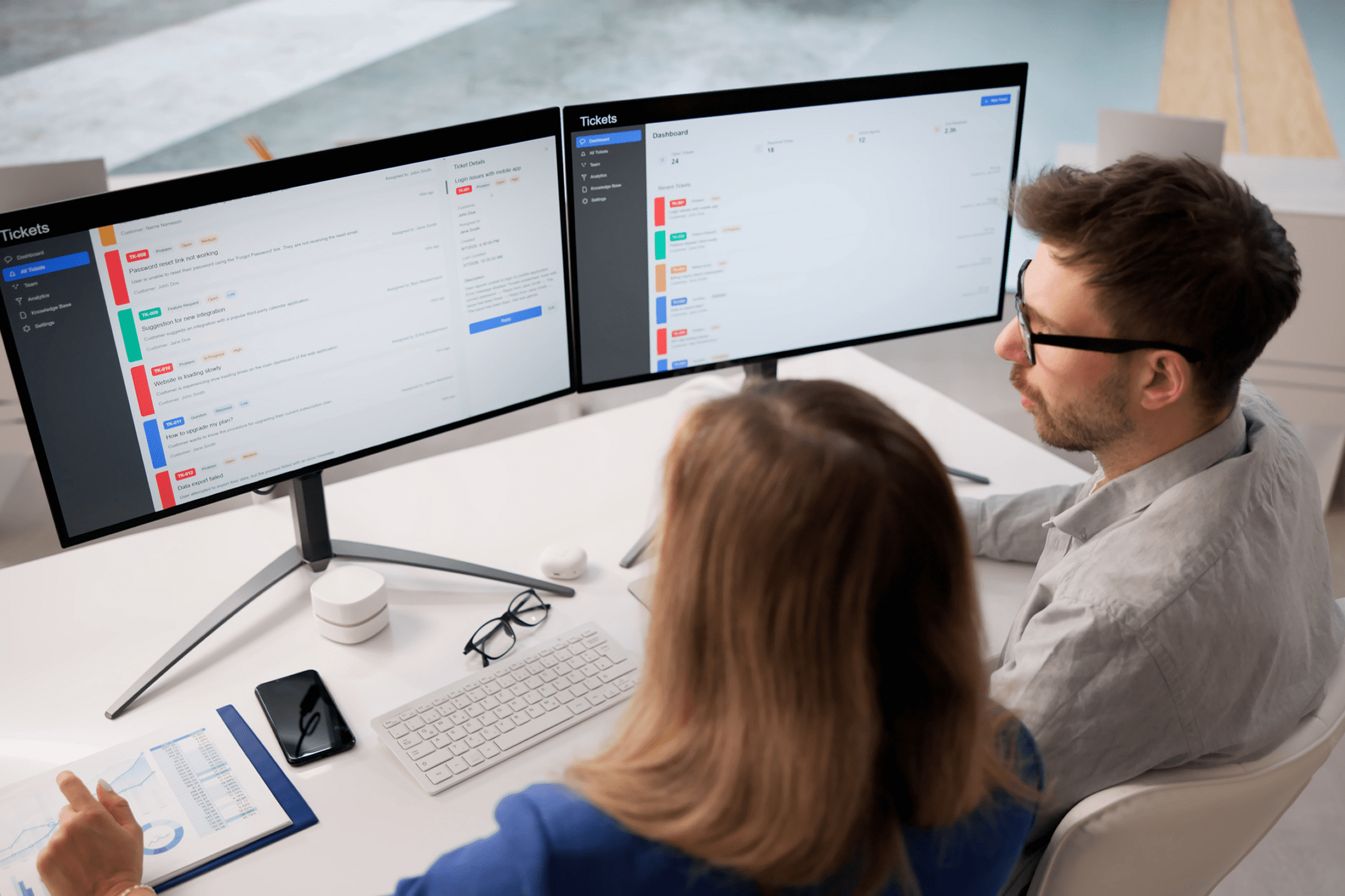 Two professionals collaborating on a project with dual monitors.
