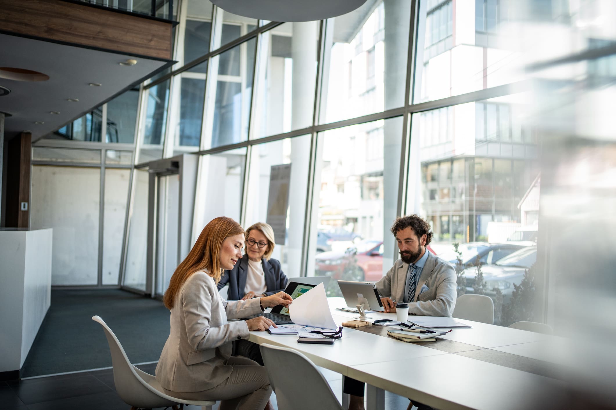 Three professionals collaborating in a modern office with laptops and documents.