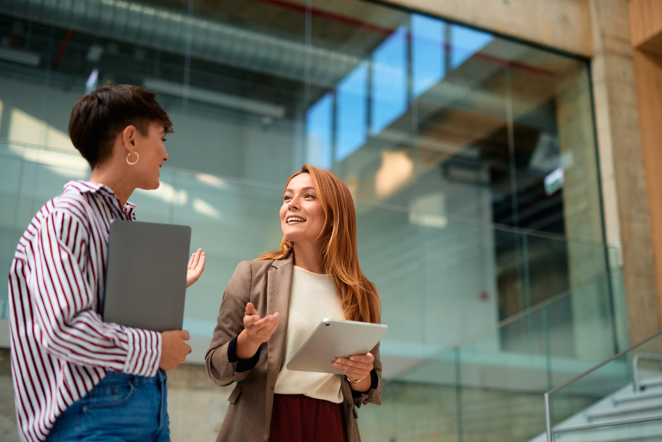 Two professionals discussing work with digital devices in a modern office.